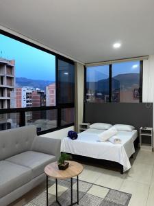 a bedroom with a bed and a couch and windows at Penthouse-Loft, Laureles, Vistas a Medellín - 801 in Medellín