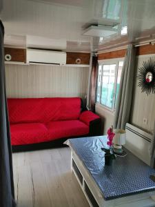 ein Wohnzimmer mit einem roten Sofa und einem Tisch in der Unterkunft SOUS LE SOLEIL DE PROVENCE in Le Castellet
