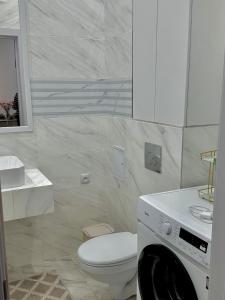 a bathroom with a toilet and a washing machine at Stay Inn - 2-х комнатная квартира комфорт класса in Taldykolʼ