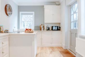 a kitchen with white cabinets and a bowl of fruit on the counter at The Harrogate Townhouse in Harrogate