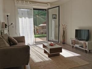 ein Wohnzimmer mit einem Sofa und einem TV in der Unterkunft Joli Appartement +Jardin privé in Cergy