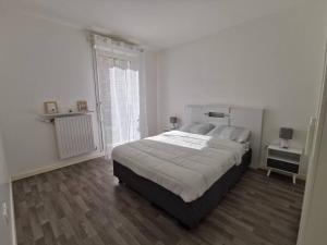 ein weißes Schlafzimmer mit einem großen Bett und einem Fenster in der Unterkunft Joli Appartement +Jardin privé in Cergy