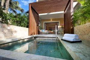 a swimming pool in a villa with a white chair at TRS Yucatan Hotel - Adults Only in Akumal