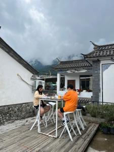 two people sitting at a table on a deck at Monster B&B in Dali