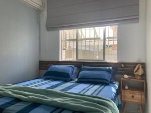 um quarto com uma cama com almofadas azuis e uma janela em Apartamento Santinho em Florianópolis