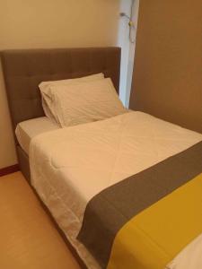 マニラにあるHomey 1Bedroom BGC Condo - MINIMUM 2 Nights stayのベッド(茶色のヘッドボード、白いシーツ付)