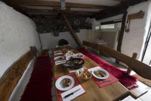 a wooden table with plates of food on it at Mountain Cottage Mons Baebius in Starčevića Podi