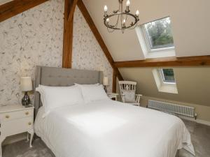 a bedroom with a white bed and two windows at Cuckoo Penn Hideaway in Stonehouse