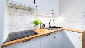 a kitchen with white cabinets and a sink at Apartament Lux pod Karpaczem in Miłków