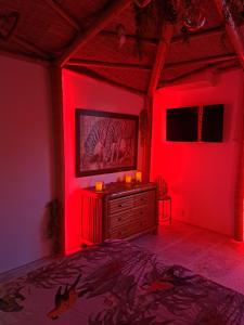 - une chambre avec un éclairage rouge et un lit avec une commode dans l'établissement Mas des rochers - Case bambou, au Beausset