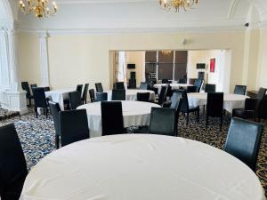 een kamer met witte tafels en stoelen en kroonluchters bij Adamton Country House Hotel in Prestwick