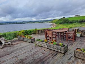 a wooden deck with a table and benches and flowers at Buncronan Port Self Catering in Donegal