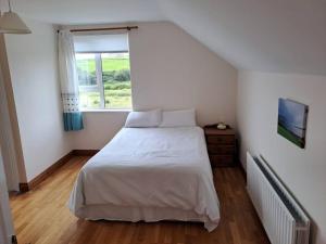 a bedroom with a white bed and a window at Buncronan Port Self Catering in Donegal +4 photos