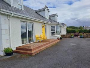 ein Haus mit einer Terrasse mit zwei gelben Stühlen darauf in der Unterkunft Buncronan Port Self Catering in Donegal