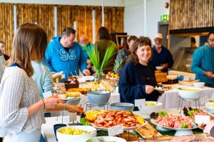 grupa ludzi stojących wokół bufetu z jedzeniem w obiekcie Bergen Hostel Montana w Bergen