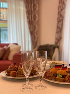 a table with two plates of food and two wine glasses at Garnì Villa Elsa in Pozza di Fassa