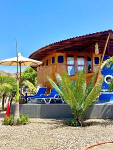 una casa con tumbonas azules y sombrilla en Hotel Casa Playa Zorritos en Zorritos