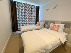 a bedroom with two beds and a window at Cozy 2B2B Apartment with Free Parking & Penthouse Pool in Box Hill