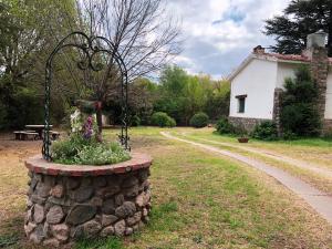 una pared de piedra con una maceta de flores en un patio en Villa Vazquez - Chalet con Quincho en La Falda