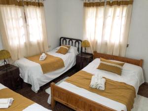 1 dormitorio con 2 camas y toallas. en Villa Vazquez - Chalet con Quincho en La Falda
