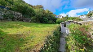 a small shed in a grassy field next to a building at Bay Cottage in Portloe