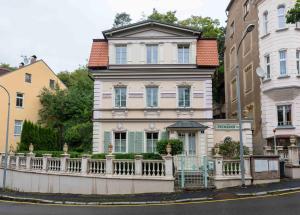 una grande casa bianca con una recinzione di fronte di Rezidence Palmbaum - luxury and relax a Karlovy Vary