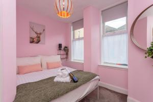 une chambre rose avec un lit avec un animal rembourré dans l'établissement Warm 1bed Flat Leith Walk, à Édimbourg