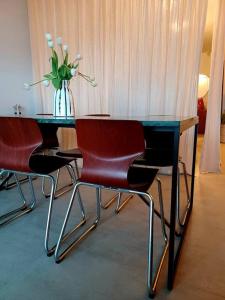 een tafel met drie stoelen en een vaas met bloemen bij The Banker Antwerpen - Free Parking in Antwerpen