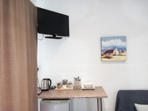 um quarto com uma mesa e uma televisão na parede em 7 On Grey Guesthouse em Colesberg