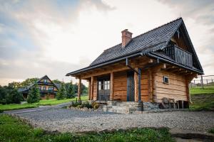 a log cabin with a house in the background at Sokolisko - domki całoroczne z kominkiem in Wysoczany
