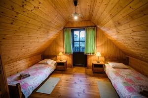 a attic room with two beds and a window at Sokolisko - domki całoroczne z kominkiem in Wysoczany