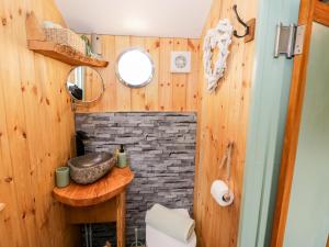 a bathroom with a stone fireplace and a sink at Cobblers Cabin in Northampton