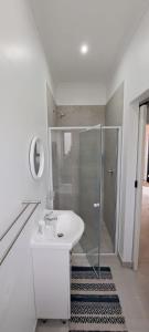 a white bathroom with a shower and a sink at Silver Oaks Luxury Guest Cottage in Langebaan