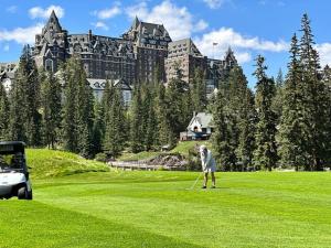 a man playing golf in front of a large building at Canmore Chalet with Hot tub at Three Sisters Mtn in Canmore