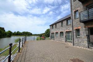 a brick building next to a river with a fence at Castle Pond House in Pembroke