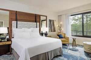 a bedroom with a large white bed and a chair at The Woodlands Resort, Curio Collection by Hilton in The Woodlands