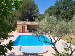 a swimming pool in front of a house with a building at Mas des rochers - Case bambou in Le Beausset