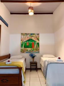 a room with two beds and a painting on the wall at Cantinho da Cineka in Caraíva