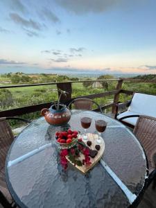 a glass table with a bowl of fruit and two glasses of wine at Chalé Adventure - Serra de São Bento RN in Serra de São Bento
