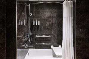 a bathroom with a shower with a tub and a toilet at AC Hotel by Marriott New Orleans French Quarter in New Orleans