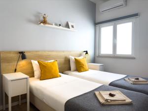 two beds in a hotel room with yellow pillows at Solar do Alentejo in Cercal