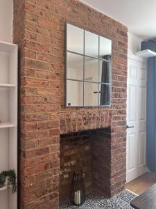 a brick fireplace with a mirror on top of it at Riverside 3 Bed House in Winchester
