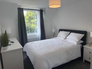 a bedroom with a white bed and a window at Riverside 3 Bed House in Winchester