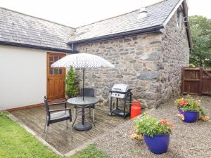 a patio with a table and an umbrella and a grill at Bwthyn Ty Newydd in Pont Dolanog