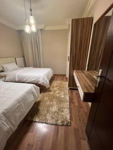 een hotelkamer met 2 bedden en een tafel bij دوبلكس بيفرلي هيلز اربع غرف الشيخ زايد فرش مودرن in Sheikh Zayed