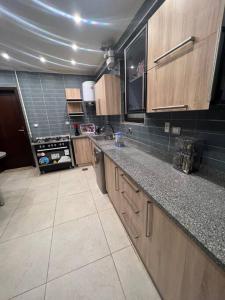 a kitchen with wooden cabinets and a tile floor at دوبلكس بيفرلي هيلز اربع غرف الشيخ زايد فرش مودرن in Sheikh Zayed