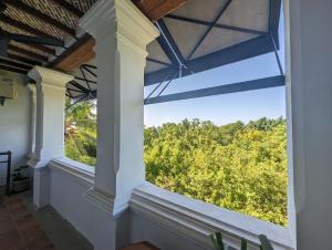een raam in een kamer met uitzicht op de bomen bij Thanga House by LuxUnlock Private Villas in Tarangambādi