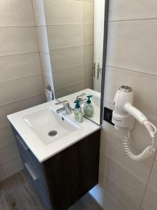 La salle de bains est pourvue d'un lavabo blanc et d'un téléphone. dans l'établissement Gigantes View Studio, à Puerto de Santiago