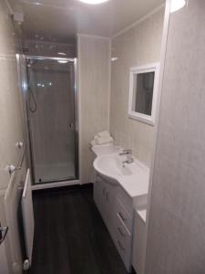 a white bathroom with a shower and a sink at The hermitage inn in Warkworth