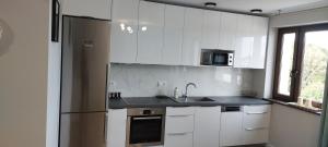 a kitchen with white cabinets and a stainless steel refrigerator at Apartament Choszczno in Choszczno